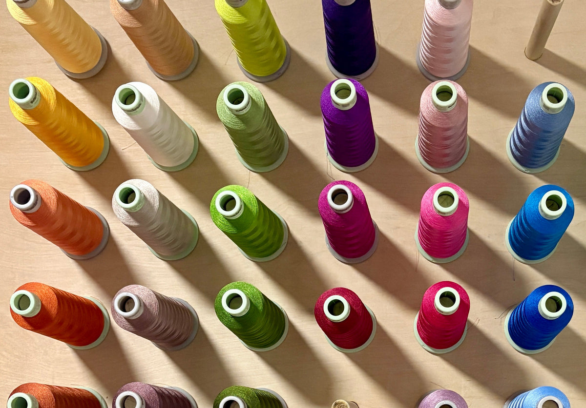 A wooden pegboard organizer filled with colorful spools of thread